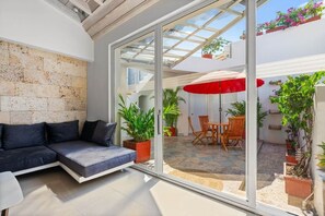 Una sala de estar moderna con pared de vidrio, un sofá y una zona de comedor con un paraguas rojo.