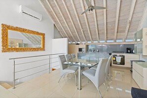 Uma cozinha moderna com uma ilha central, um espaço de jantar com mesa de vidro e um espelho grande e decorativo.