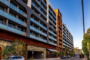 Un hotel de varios pisos con balcones, un estacionamiento y una fachada decorativa.