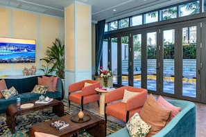 A hotel lobby with a large TV, seating area, and large windows. - The Gallery | Lux Studio in Wynwood (Miami)