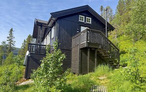 A wooden cabin with a balcony and stairs, surrounded by lush greenery and trees. - Amazing home in Skonseng with house sea view (Skonseng)