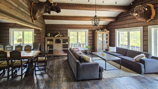 A log cabin interior with a dining area, sofa, and a mounted moose head. - Beautiful home in Hovden i Setesdal with sauna (Hovden i Setesdal)