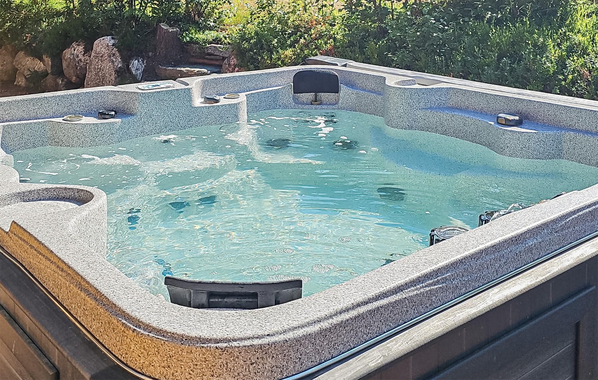 Ein Whirlpool mit Steinfassade und mehreren Sitzbereichen.