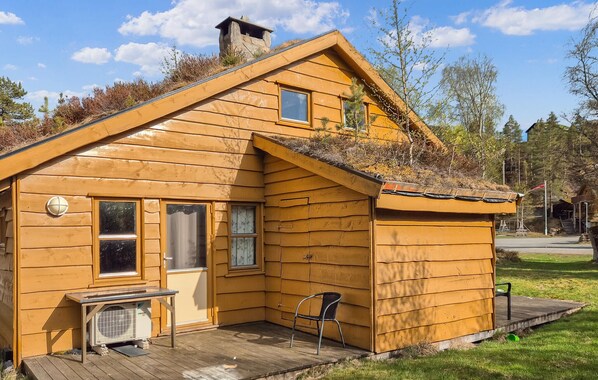 A wooden cabin with a porch, a small table, and a chair. - Stunning home in Tjørhom with sauna (Tjørhom)