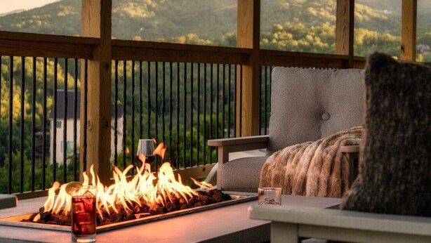 Un balcón con una chimenea exterior, una silla y vistas a las montañas.