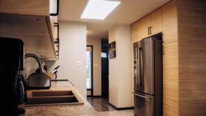 Una cocina moderna con refrigerador empotrado, un lavamanos y armarios de madera.