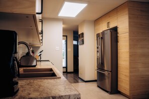 Une cuisine moderne dotée d’un réfrigérateur encastré, d’un évier et de meubles de rangement en bois.