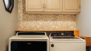 Una cocina funcional con lavadora y secadora, armarios de madera y un salpicadero decorativo.