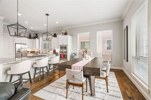 A modern kitchen with white cabinets, a central island, and pendant lighting.