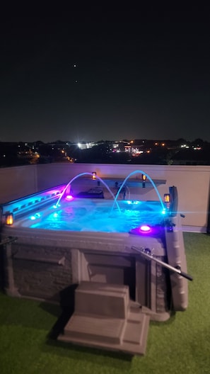 A hot tub with built-in lighting and a step leading up to it.