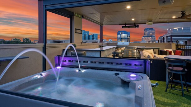 A rooftop bar with a hot tub, outdoor seating, and a city skyline view at sunset. - Sky house in LasColinas near Dallas Stadium in Arlington (Irving)