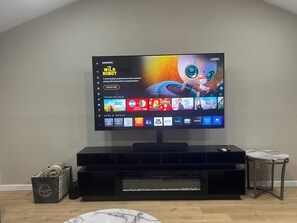 Ein Flachbildfernseher ist an einer schwarzen Unterhaltungseinheit befestigt, daneben steht ein Tisch mit Marmorplatte.
