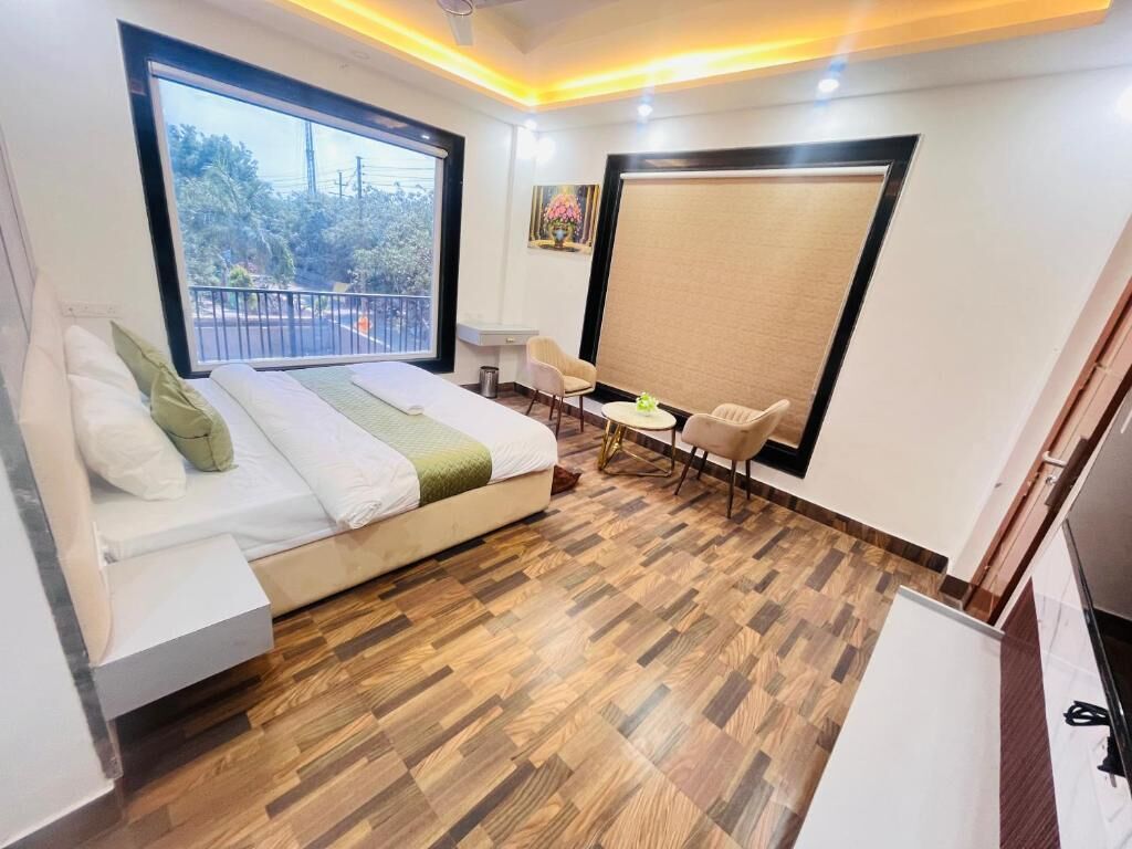 Un dormitorio con cama, una mesita, dos sillas, una ventana y un balcón.