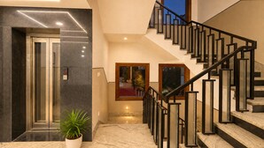 Interior moderno com escada, elevador e planta em vaso.