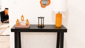 A black console table with a white lamp, orange vase, and books. - Bellevue Escape In Downtown Dallas (Dallas)