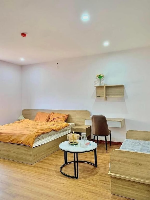Une chambre d’hôtel moderne avec un lit en bois, une table ronde, un bureau et une chaise.