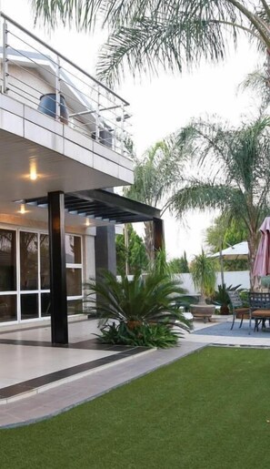 A modern building with a covered outdoor area, a pool, and a well-maintained lawn. - Cycad Palm Hotel Gaborone (Gaborone)