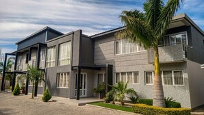 Un edificio moderno de dos pisos con techo plano, ventanas grandes y un sendero pavimentado.