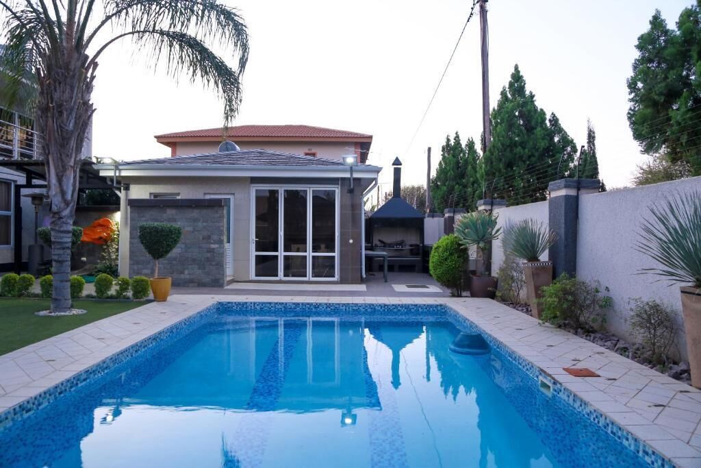A residential property with a swimming pool, a patio, and a landscaped garden.