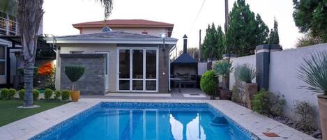 A residential property with a swimming pool, a patio, and a landscaped garden.