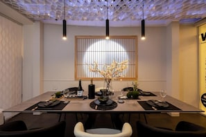 A dining area with a modern table set for four, a vase of flowers, and a bottle of wine. - JAPAVISTA Wabi (Higashimikuni)