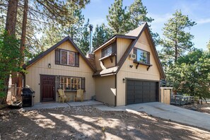 Ein zweistöckiges Haus mit Garage, Terrasse und Kamin.