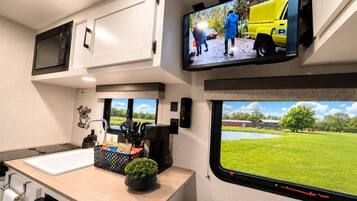 A kitchen with a sink, countertop, and a television mounted above it.