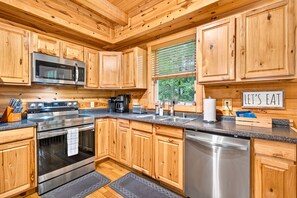 A modern kitchen with wooden cabinets, stainless steel appliances, and a 'LET'S EAT' sign. - Linden Lodge 7BR Sleeps 16 Hot Tub;Old Mans Cave (Logan)