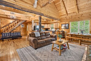 Ein Holzblockhaus-Interieur mit einer Couch, einem Couchtisch und einer Treppe.