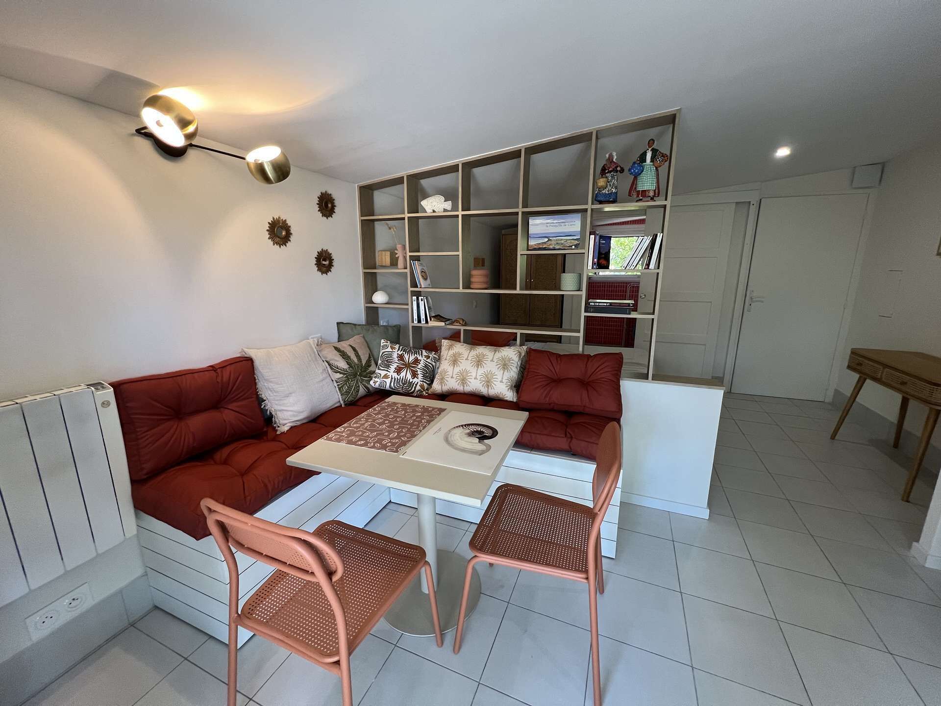Ein modernes Wohnzimmer mit einem roten Sofa, einem weißen Couchtisch und zwei Korbstühlen.