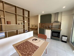 Eine moderne Küche mit Einbauofen, Kaffeemaschine und Spüle. Ein Essbereich mit Tisch und Stuhl ist ebenfalls vorhanden.