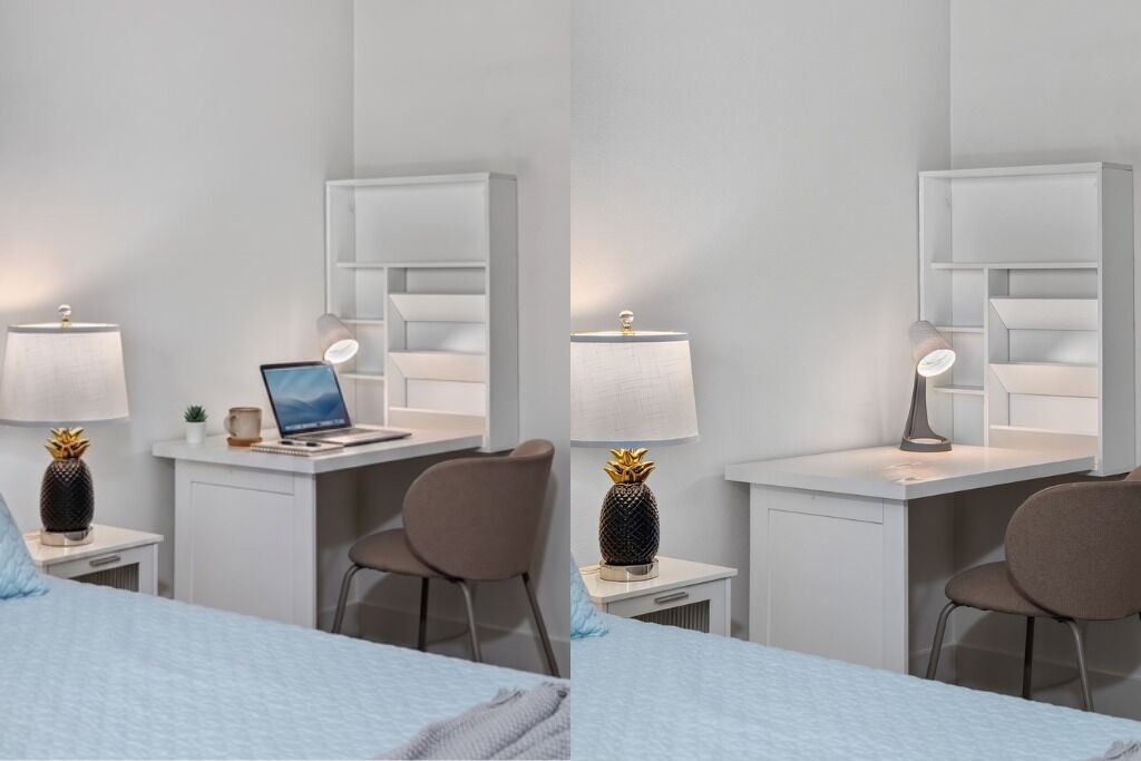 A hotel room with a bed, a desk with a laptop, a chair, a nightstand with a lamp, and a wall-mounted shelf.