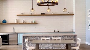 Una cucina moderna con isola centrale, illuminazione a sospensione e zona pranzo con sedie.