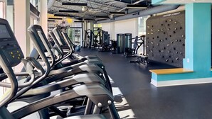 Una palestra con tapis roulant, macchinari per pesi e una parete di arrampicata.