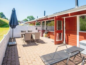 Un patio con mobiliario exterior, una parrilla y una zona de estar cubierta.