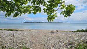Ein Kiesstrand mit einem Picknicktisch und einem Pfad zum Wasser.
