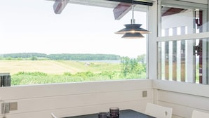 Ein Essbereich mit Tisch, Stühlen und Blick auf eine grüne Landschaft durch ein Fenster.