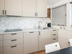Una cocina moderna con encimeras de mármol, estufa integrada y una ventana con vistas.