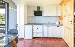 A compact kitchen with white cabinets, a microwave, a sink, and a glass table. - Stunning home in Mscice (Mscice)