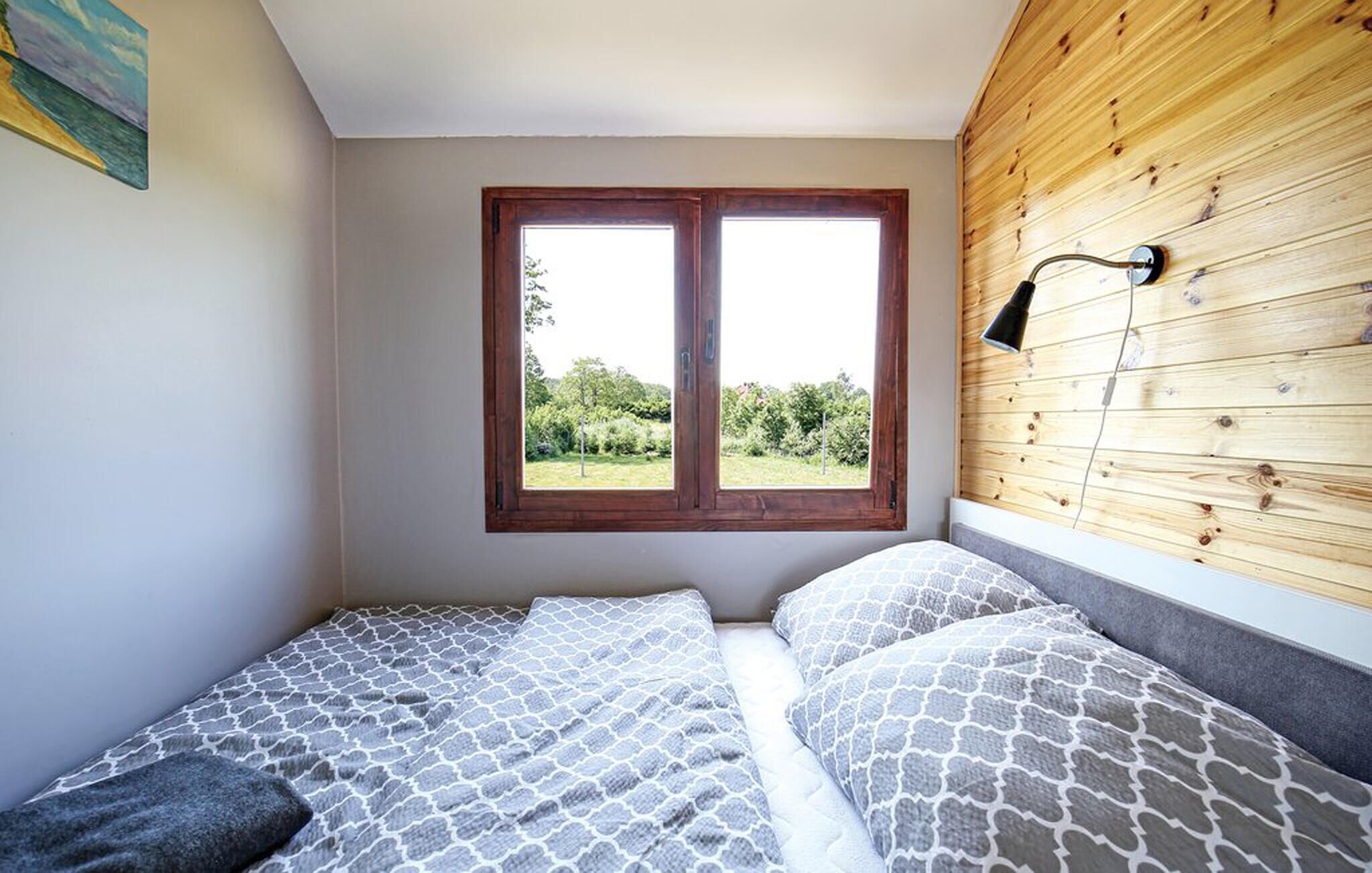 Quarto com cabeceira de madeira, janela com vista para áreas verdes e cama com roupa de cama estampada.