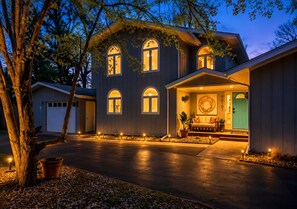 Ein zweistöckiges Haus mit Veranda, Garage und Auffahrt.