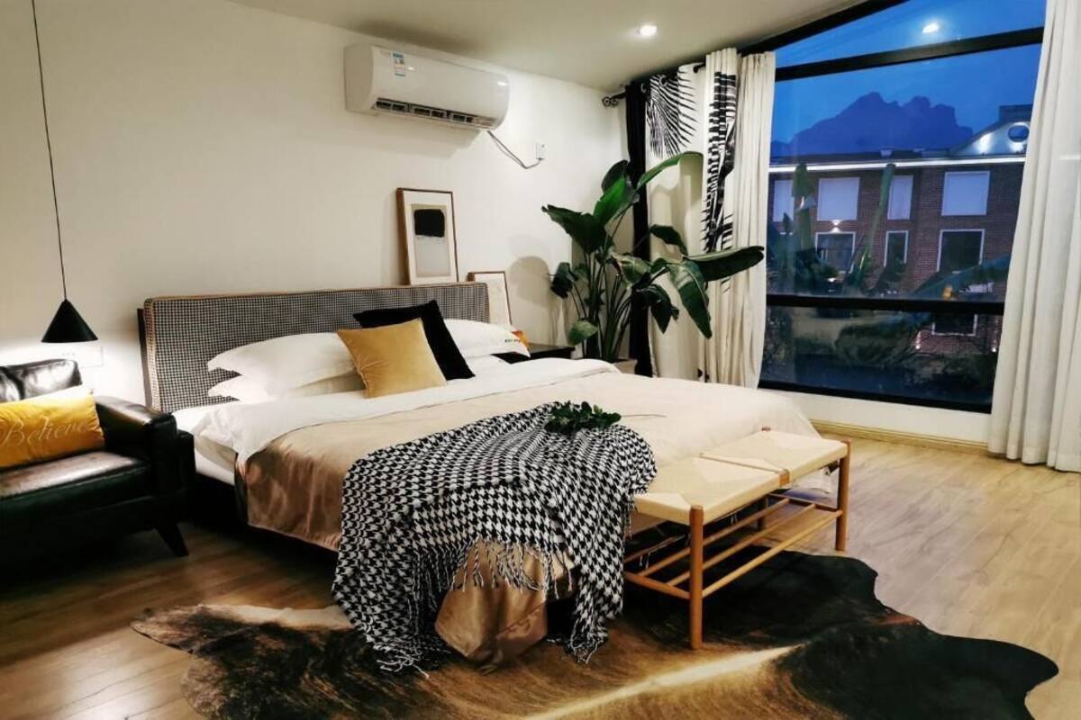 Een slaapkamer met een bed, nachtkastje, lamp en uitzicht.