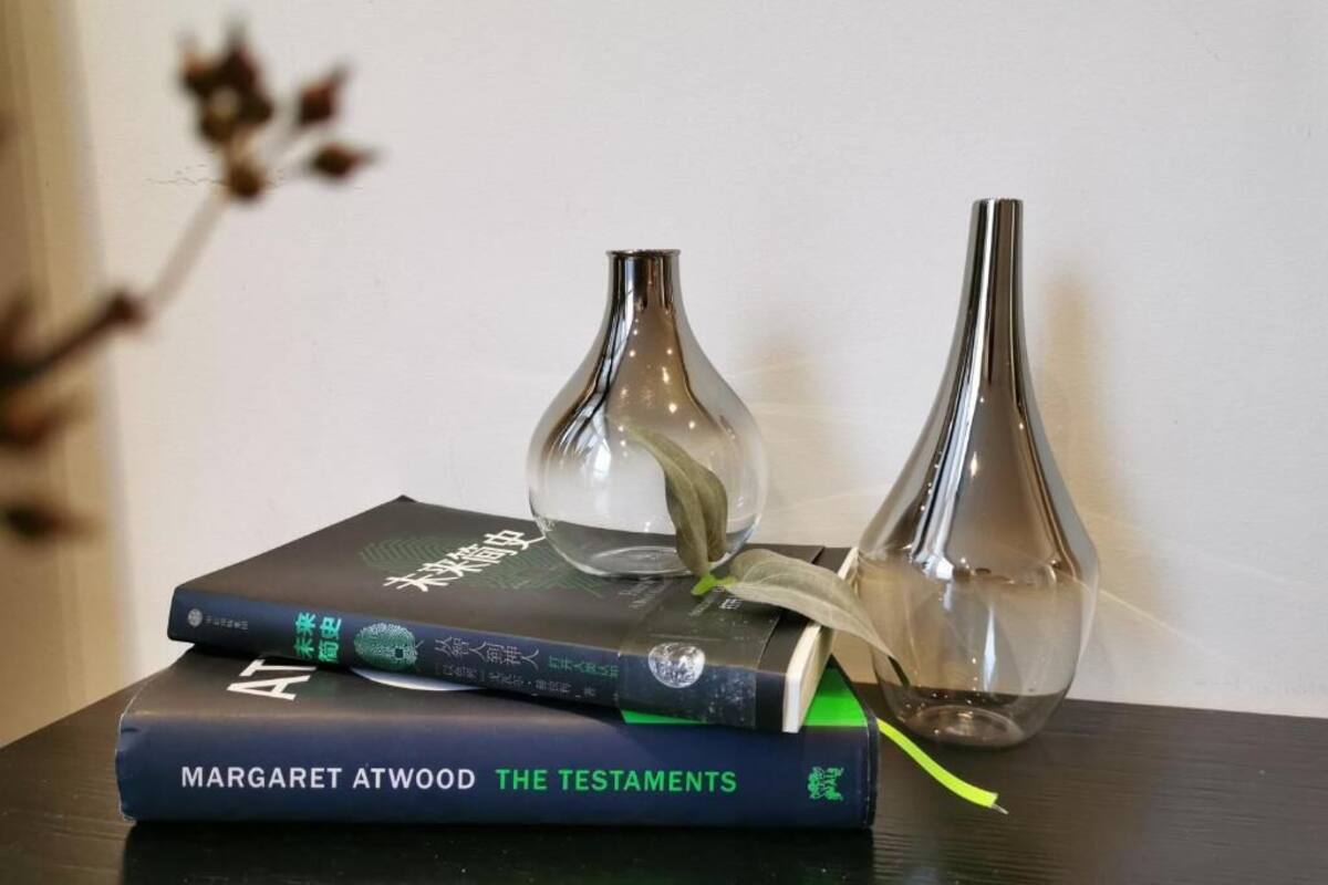 Een stapel boeken met een glazen vaas erboven.