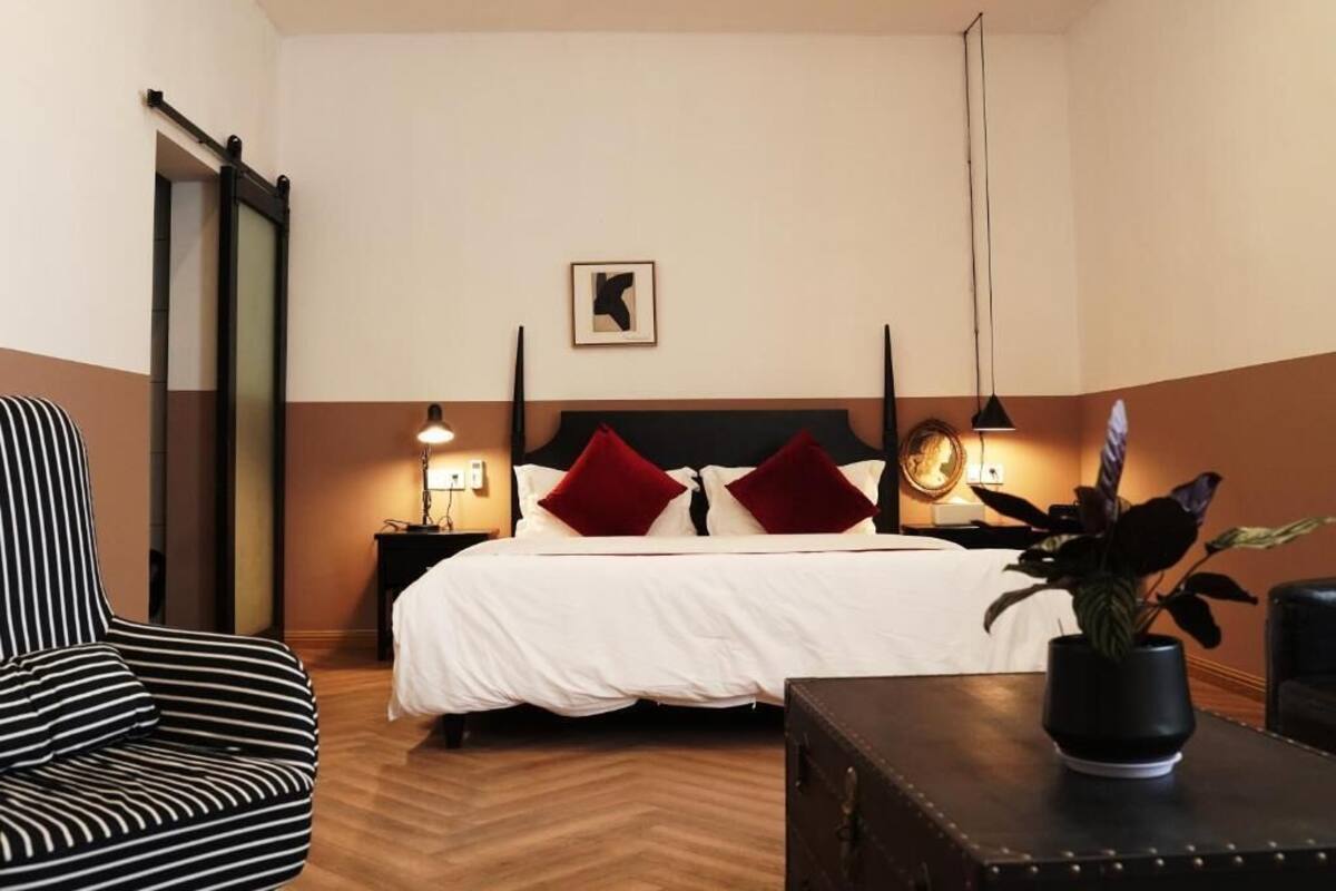 Een hotelkamer met een bed, bedlampen, een stoel, een tafel en een plant.