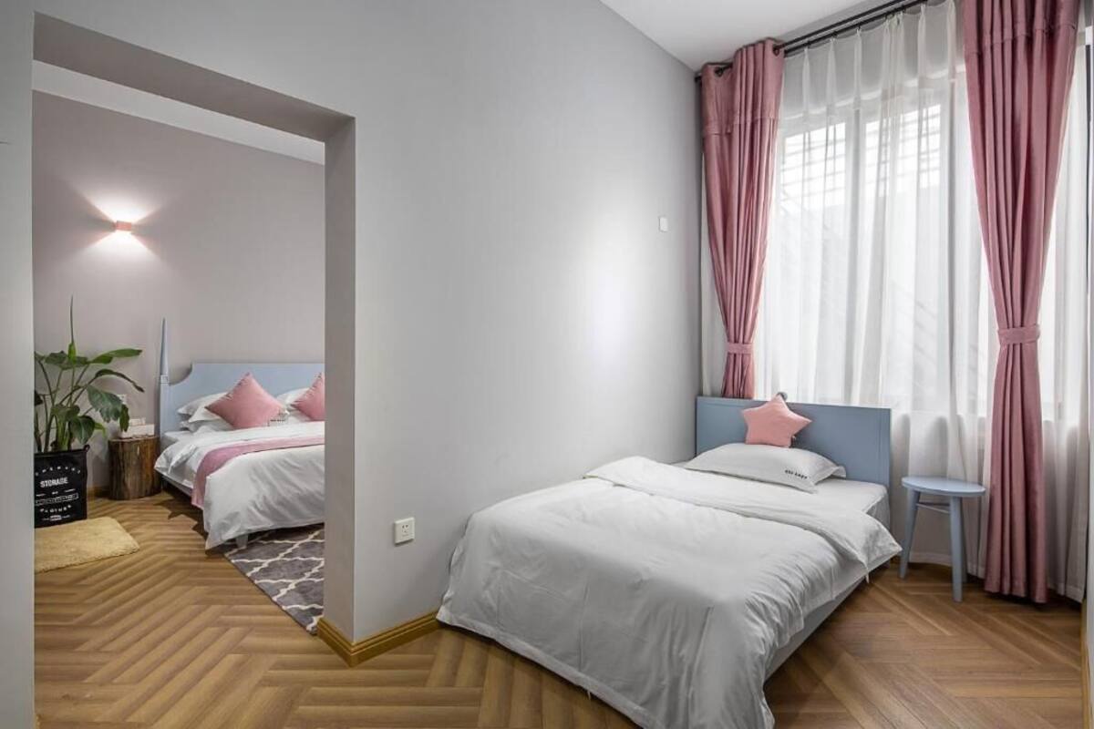 Een slaapkamer met twee bedden, een klein tafeltje, een bloempot en een lamp.
