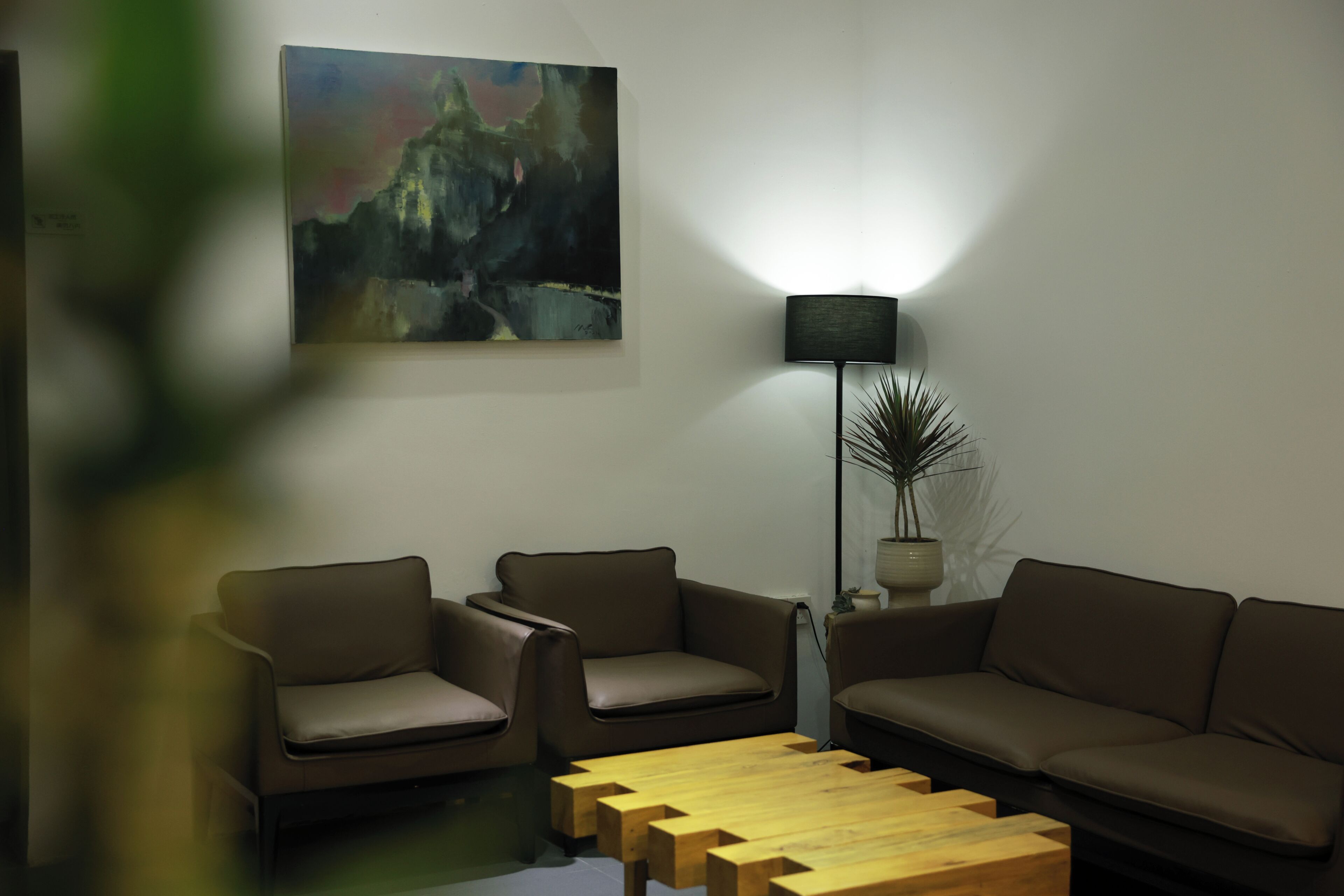 Una sala de estar moderna con un conjunto de sofá, una mesa de centro de madera, una lámpara de pie y un cuadro en la pared.