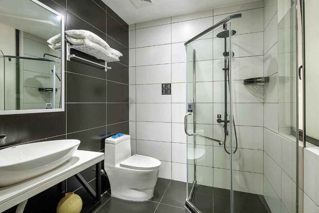 A modern bathroom with a glass-enclosed shower, a white sink, and a toilet.