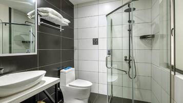 A modern bathroom with a glass-enclosed shower, a white sink, and a toilet.