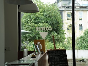 A coffee shop interior with a window view, a chalkboard with prices, and a wooden counter. - Zhangjiajie Thirty One  (Zhangjiajie)