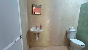Et lille badeværelse med vask, toilet og et spejl.